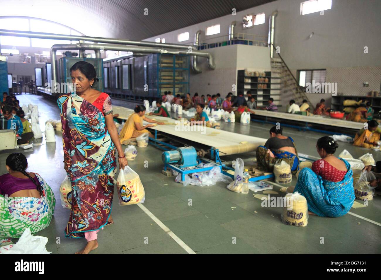 Anand, Gujarat, Indien. 21. September 2013. Einheimische Frauen arbeiten in einer Fabrik Papadum zu leben. Kinderlose Paare aus der ganzen Welt gehen auf den staubigen Straßen von Indiens Hinterland auf der Suche nach ein leibliches Kind durch Leihmutterschaft. Kommerzielle Leihmutterschaft in vielen Ländern nicht erlaubt ist, und dies bot Gelegenheit für Indien zu kapitalisieren Leihmutterschaft als ein wachsender Bereich seiner boomenden medizinischen Tourismus-Industrie einen geschätzten jährlichen Wert von $ 2,3 Milliarden hat. Mehr als 680 Babys wurden in Akansha Klinik, Leihmütter, meist aus armen Dörfern, über die letzten ni geboren Stockfoto