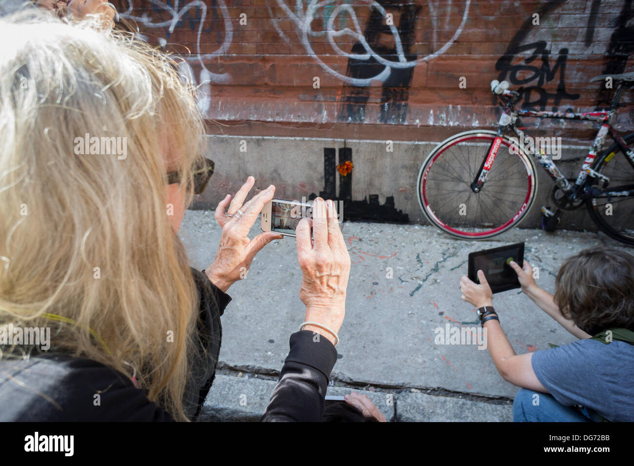 New York, USA. 15. Oktober 2013. Street-Art-Fans strömen in Stadtteil Tribeca New York auf Dienstag, 15. Oktober 2013, der fünfzehnte Ausgabe von Banksy-Graffiti-Kunst, "Tribecca" zu sehen. Die schwer fassbare Streetart-Künstler schafft Werke rund um die Stadt jeden Tag im Laufe des Monats Oktober und dieser Ausgabe zeigt eine Silhouette des World Trade Centers mit einer Blume befestigt. Bildnachweis: Richard Levine/Alamy Live-Nachrichten Stockfoto