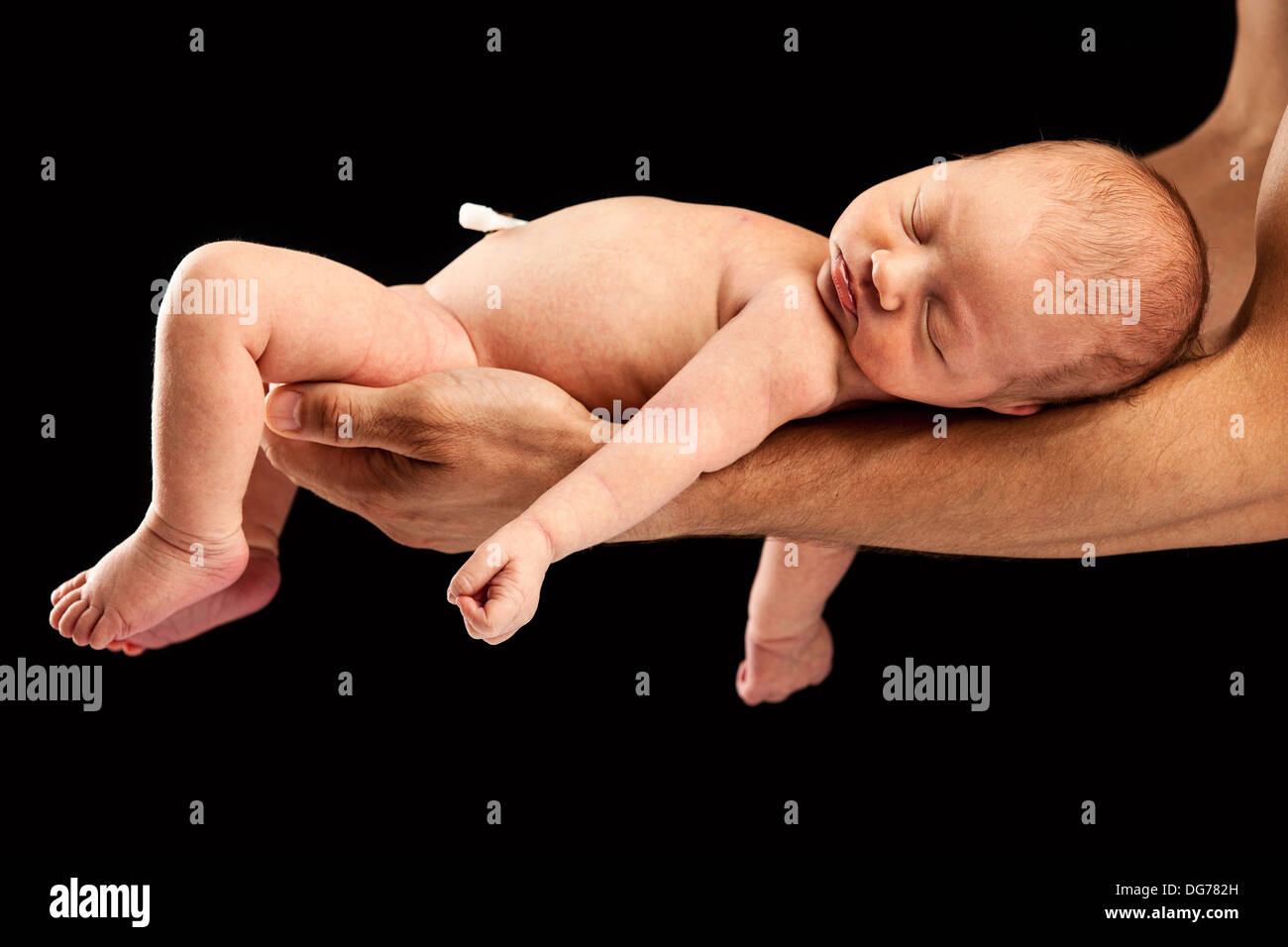 Neugeborenen jungen liegen auf seines Vaters Arme auf schwarzem Hintergrund Stockfoto