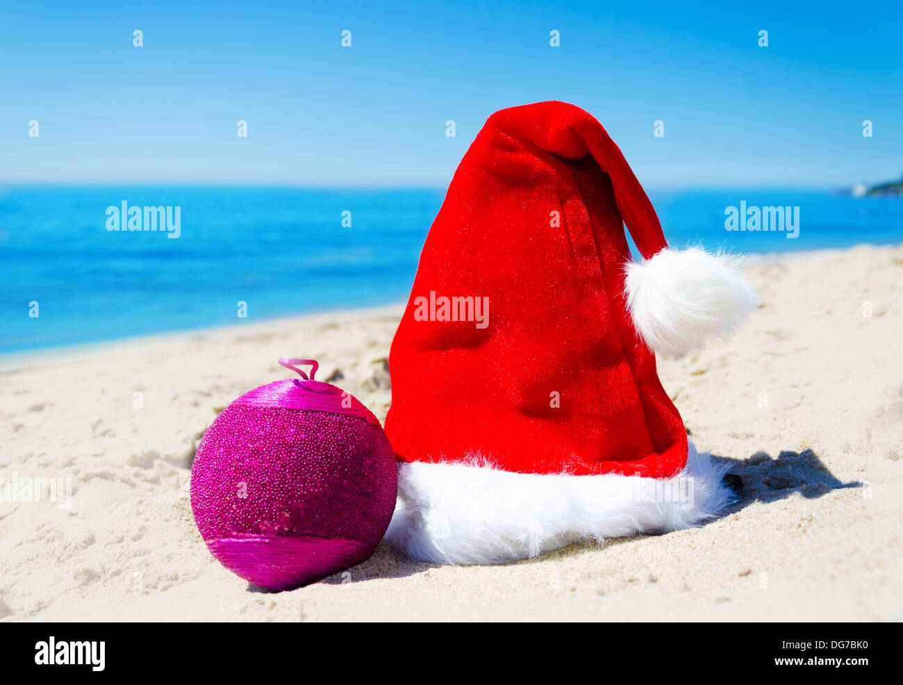Weihnachtsmütze mit Weihnachtskugel am Strand am Meer - Urlaub-Konzept Stockfoto