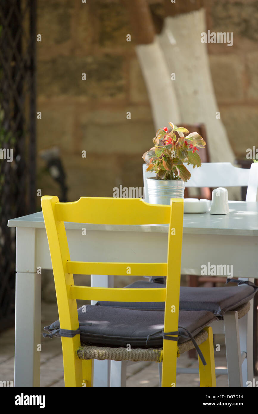 Nahaufnahme von einem gelben Stuhl und weißen Tisch. Eine traditionelle Terrasse eines Restaurants in Kreta, Griechenland 2013. Stockfoto