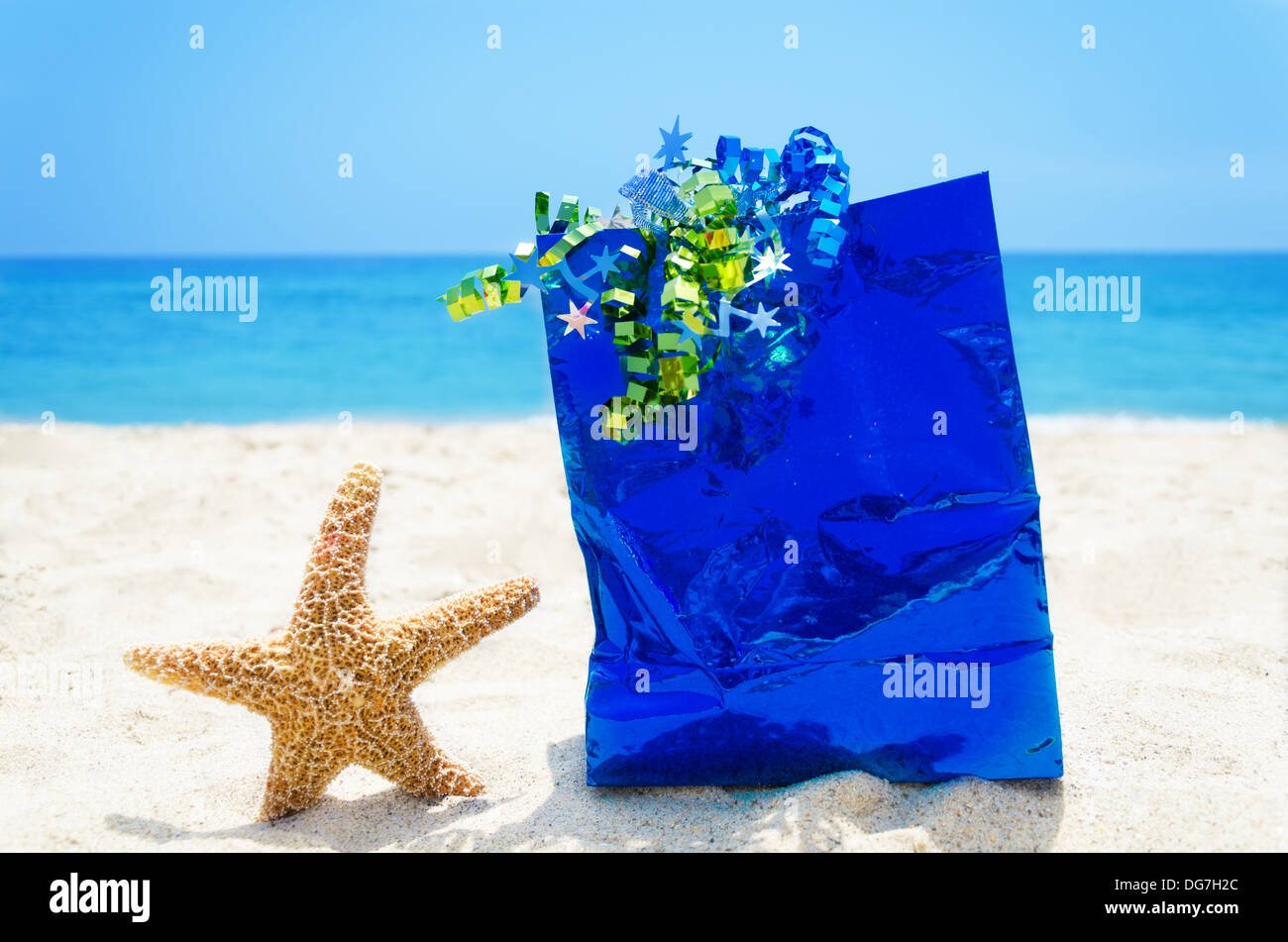 Seestern mit blauen Geschenktüte am Sandstrand in sonnigen Feiertag Konzept Stockfoto