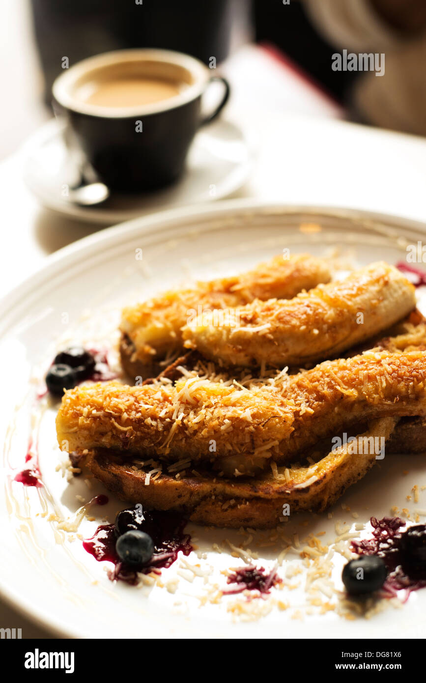 Frühstück mit gebratenen Bananen, Kokosnuss und Obst.  Und Kaffee. Stockfoto