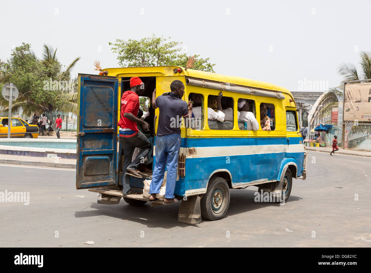 Senegal St. Louis. Junge Männer stehen oft auf dem Trittbrett an der Rückseite des lokalen Minibusse, die Bereitstellung von städtischen Nahverkehrs. Stockfoto