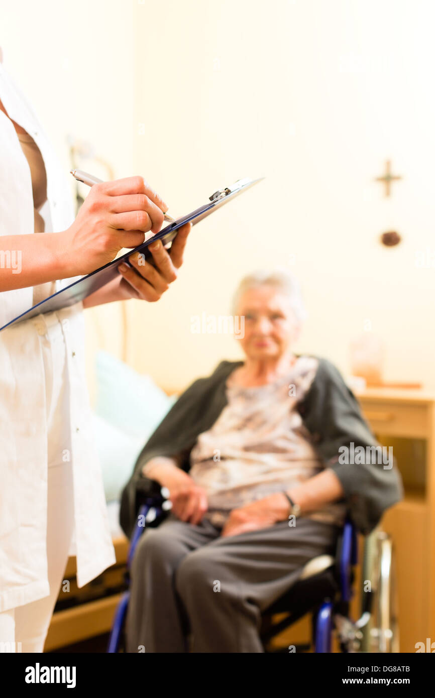 Junge Krankenschwester und weiblichen Senioren im Pflegeheim sind Messungen genommen oder administrativen Aufgaben erledigt Stockfoto