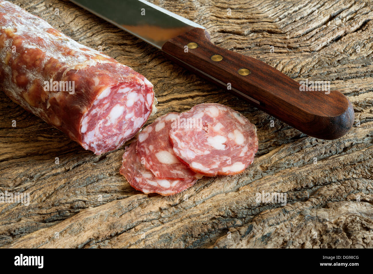 echte Salami in Scheiben geschnitten auf alten Holztisch Stockfoto