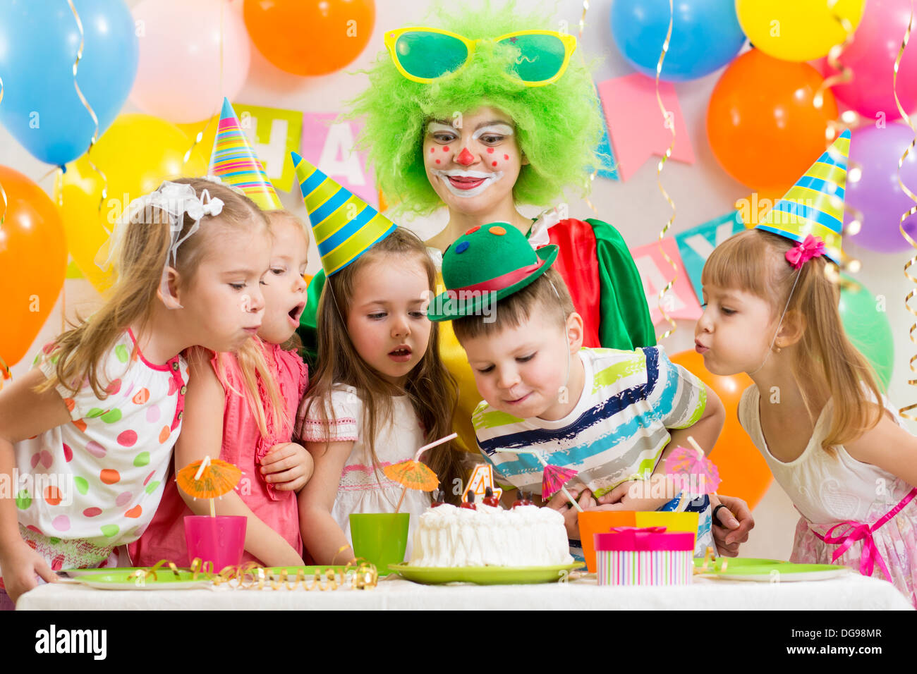 Kinder mit Clown Geburtstagsparty feiern und bläst Kerze auf Kuchen Stockfoto