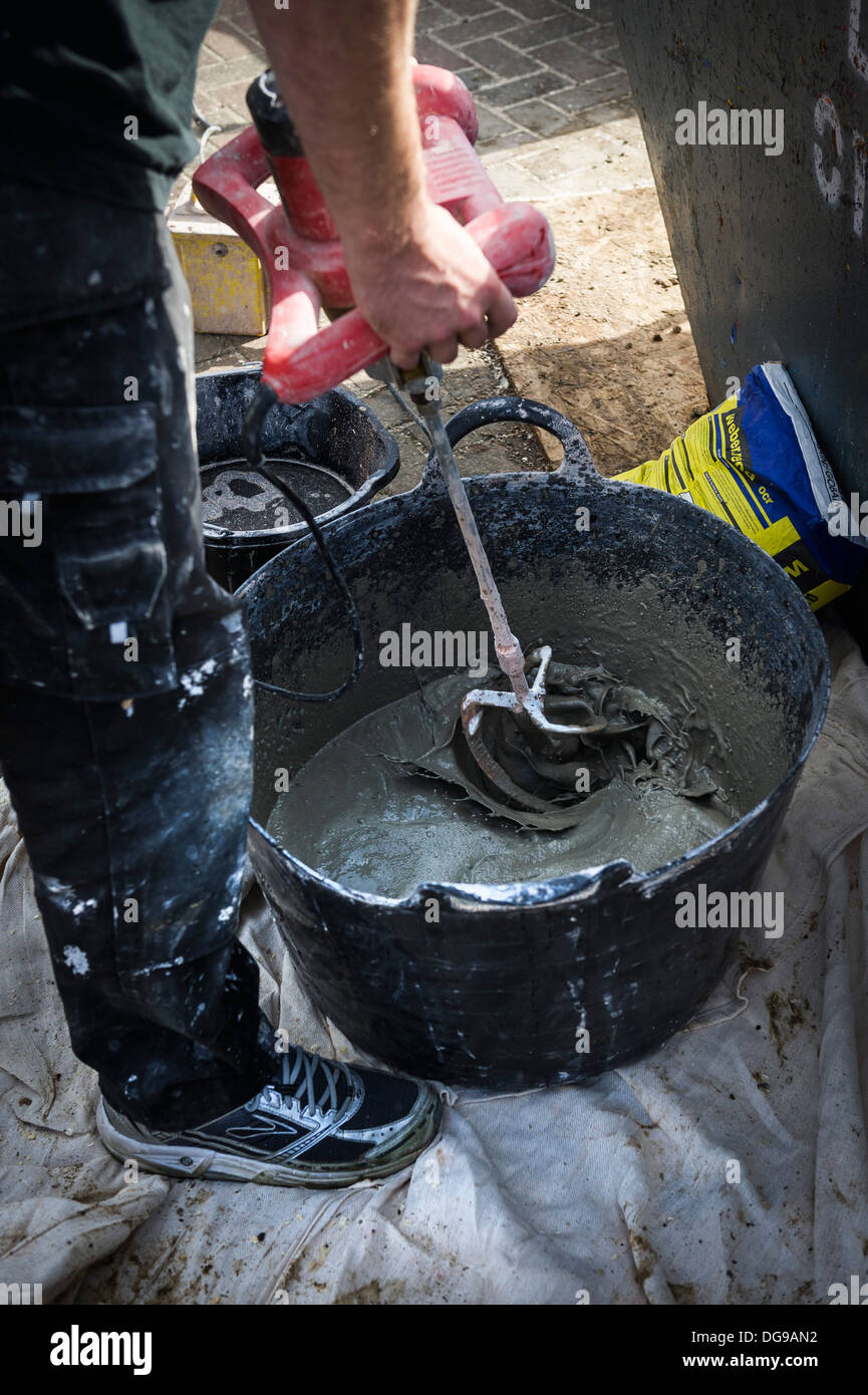 Ein Arbeiter mit einem Elektrowerkzeug Beton mischen Rendern in einer Wanne. Stockfoto
