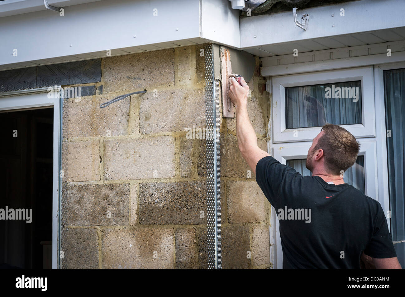Ein Arbeiter Rendern einer Außenwand eines Hauses. Stockfoto