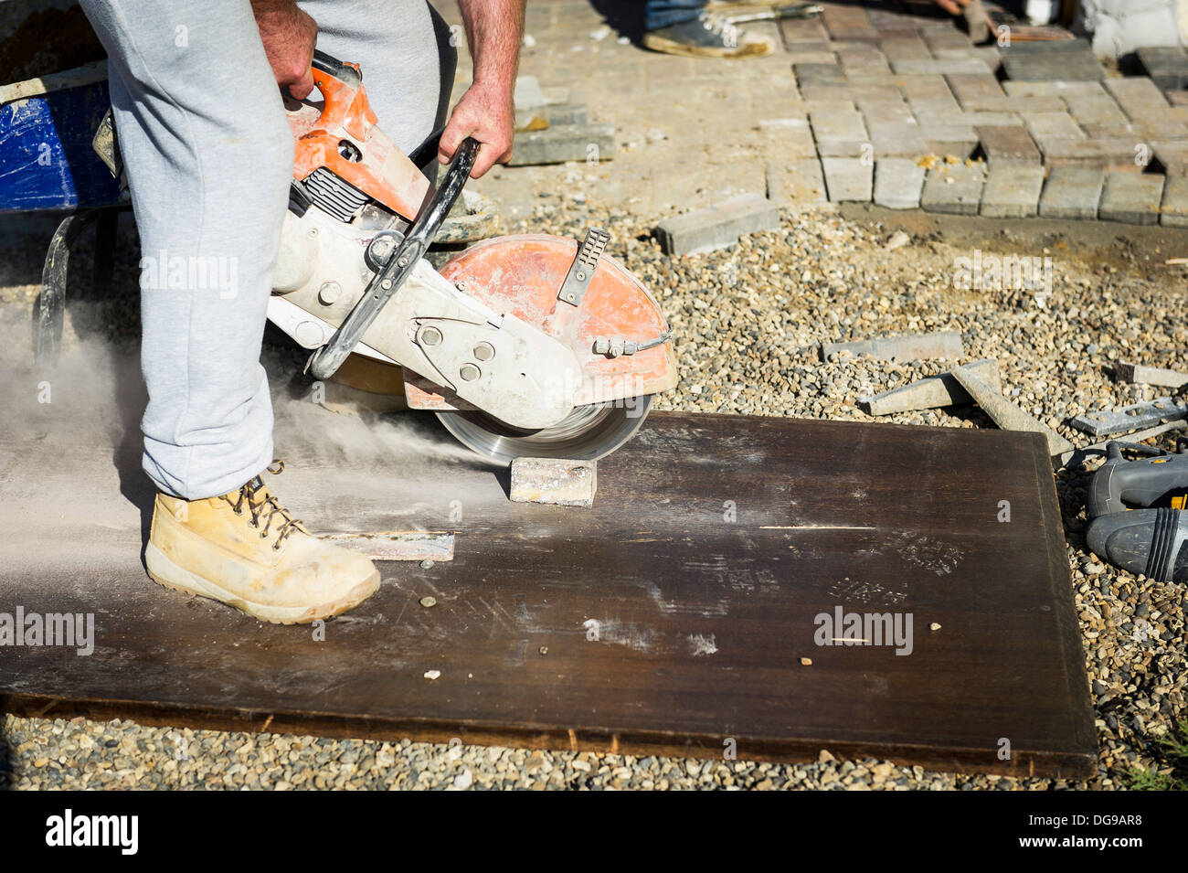 Ein Arbeiter mit einem Scheibenfräser, einen Pflaster-Block geschnitten. Stockfoto