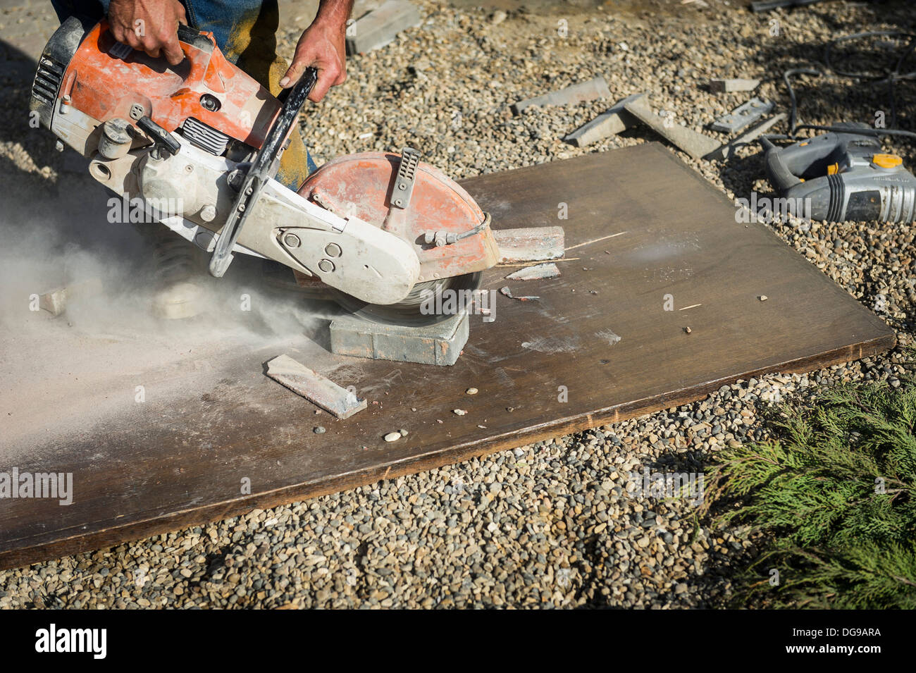 Ein Arbeiter mit einem Scheibenfräser, einen Pflaster-Block geschnitten. Stockfoto