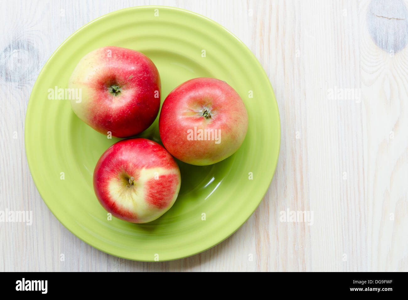 drei rote Apfel auf die grüne Platte Stockfoto
