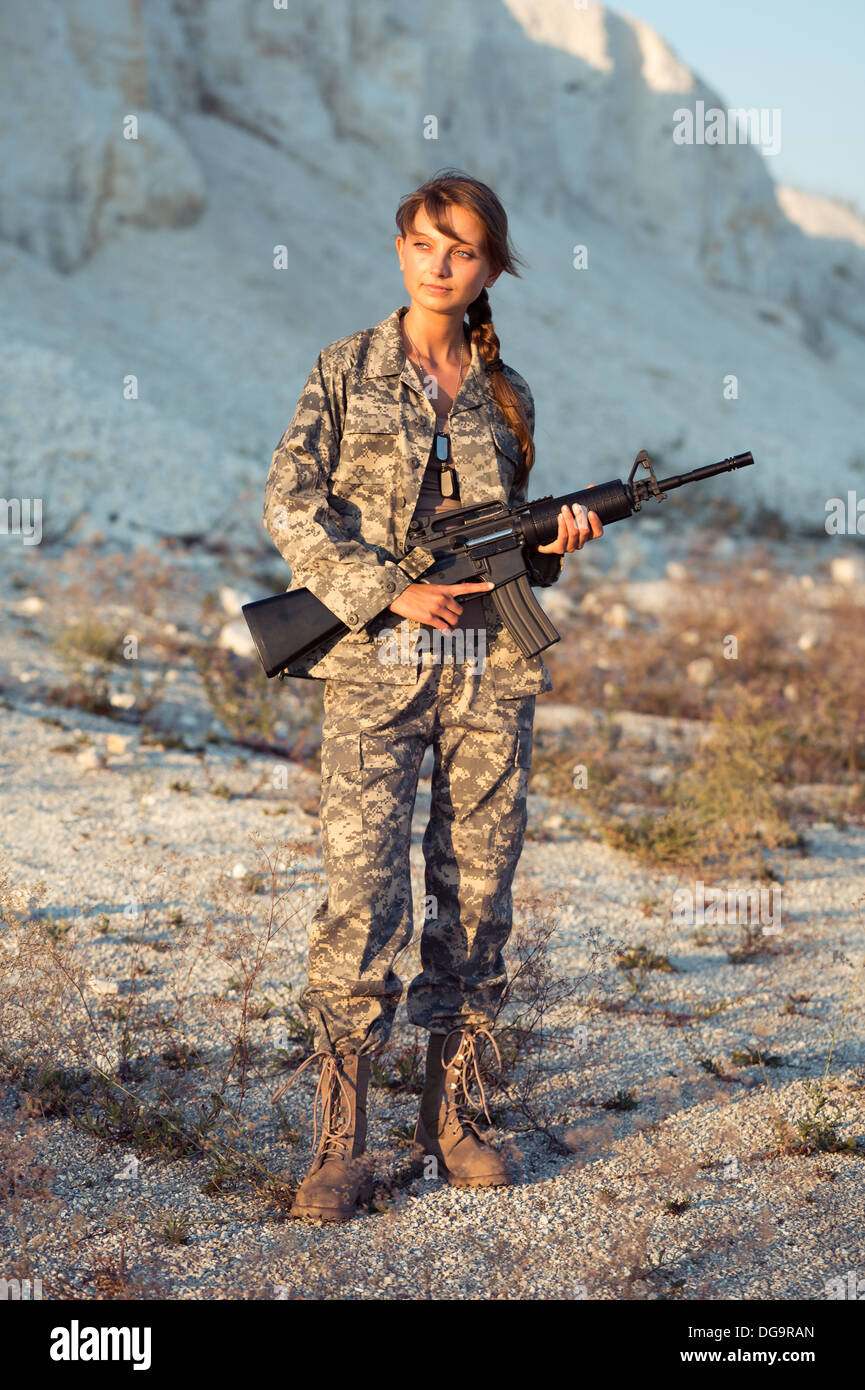 Junge schöne Soldatin, gekleidet in eine Tarnung mit einem Gewehr in der Lage Stockfoto