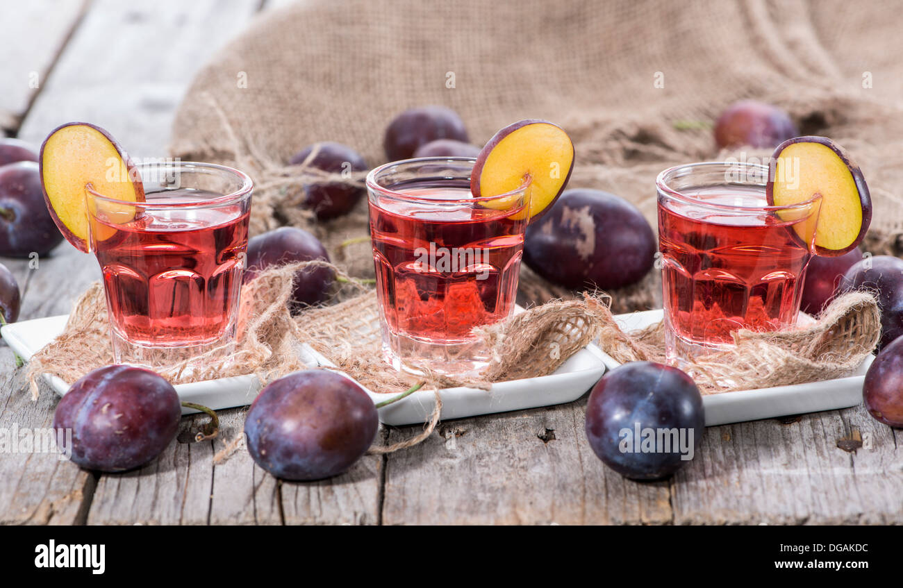 Glas mit Pflaume Likör auf hölzernen Hintergrund Stockfoto