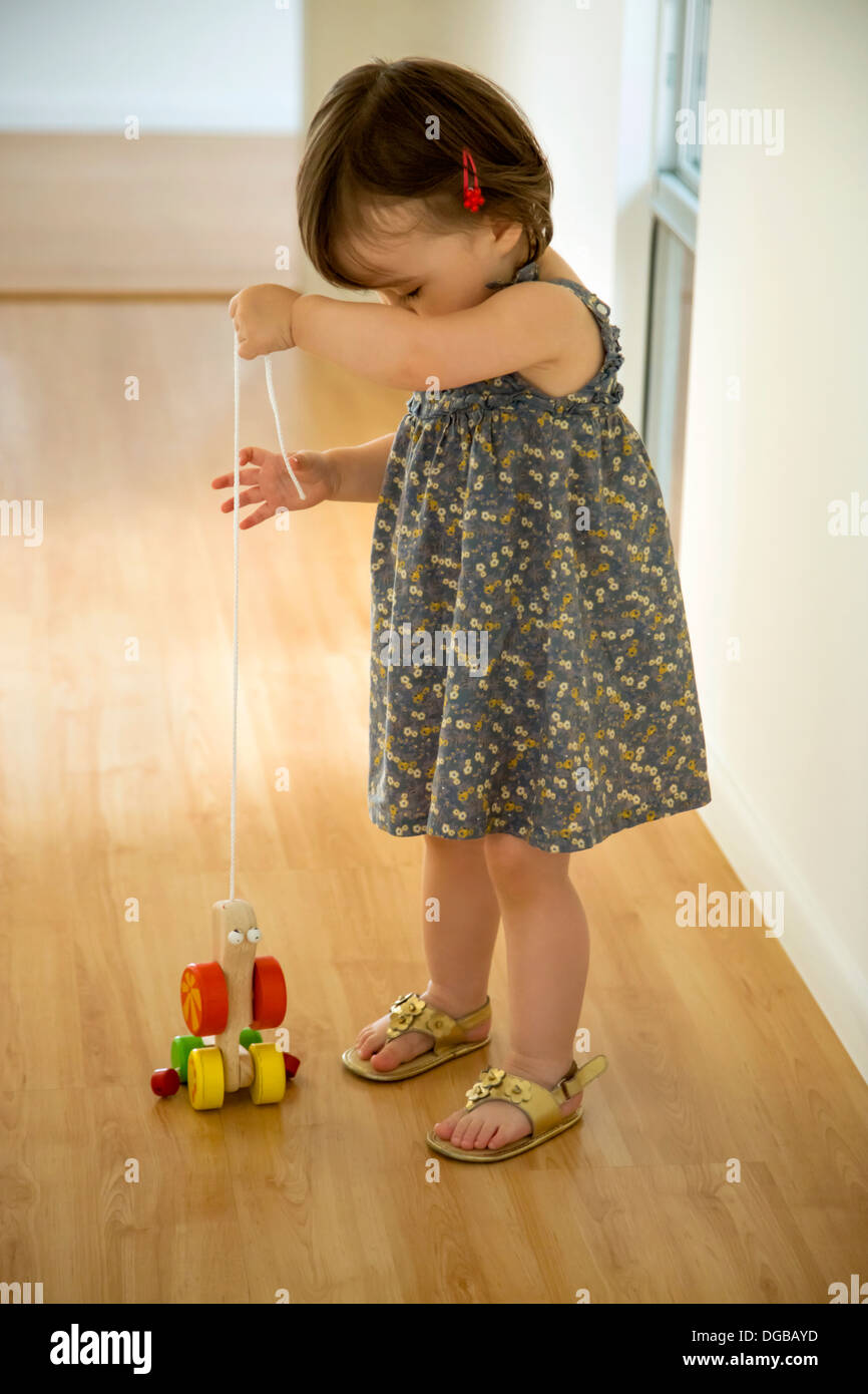 Babymädchen spielen mit einem hölzernen Spielzeug an einer Schnur Stockfoto