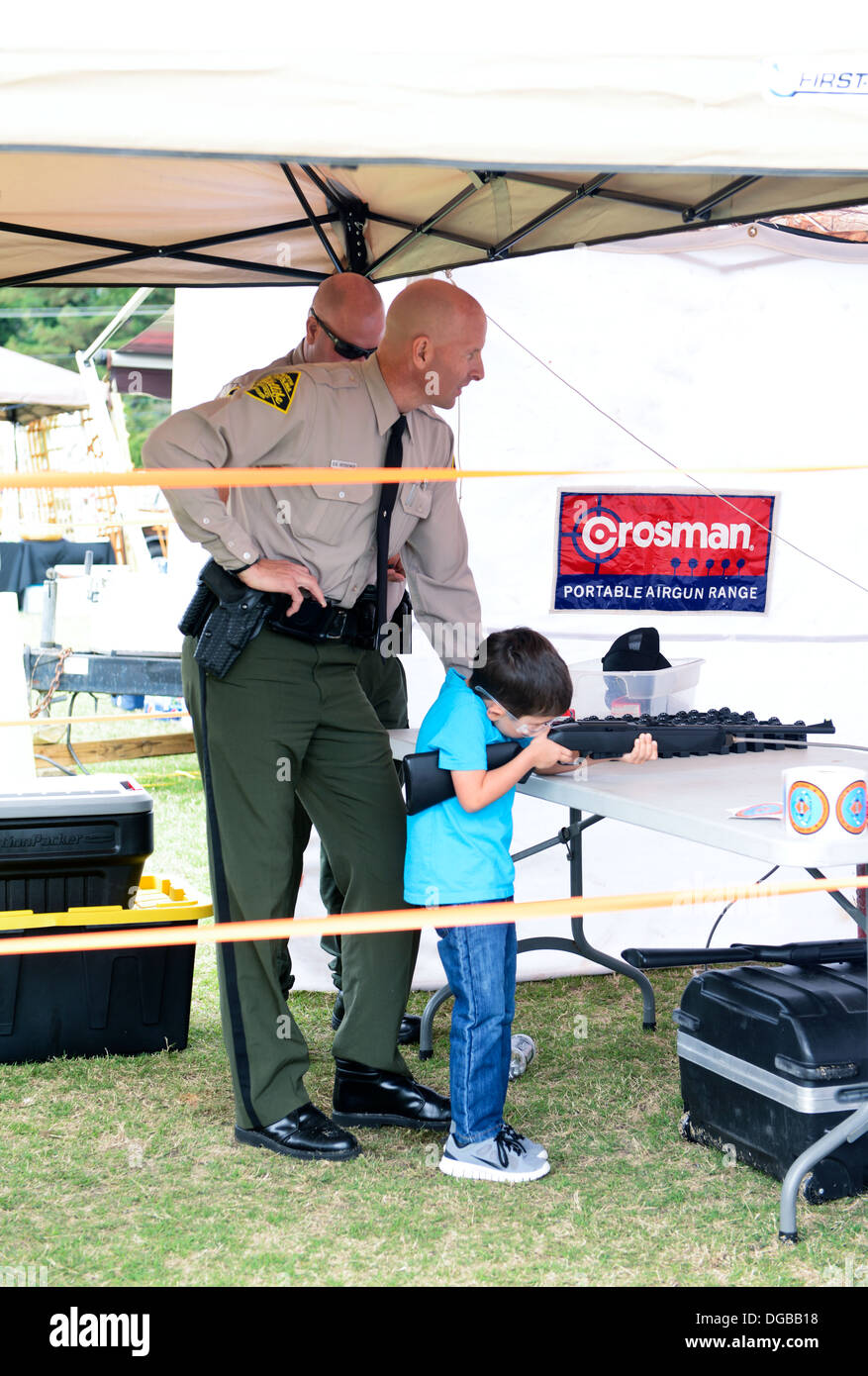 Officer Ritzheimer von North Carolina Wildlife Resources Commission hilft einen jungen Mann ein Luftgewehr schießen. Stockfoto
