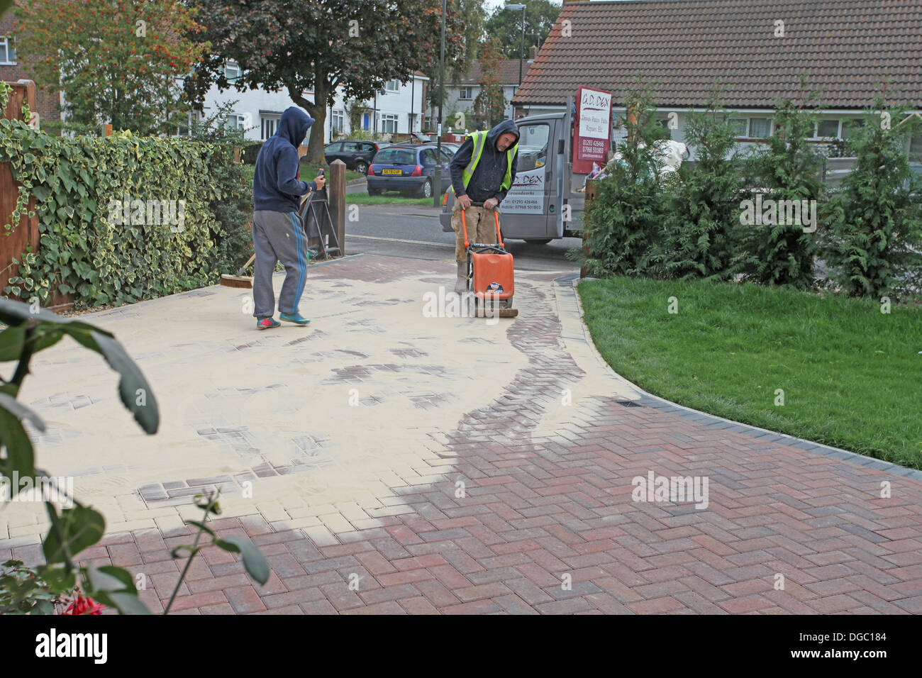 6. Etappe eines Projekts einen Block legen gepflastert Laufwerk. Verbreitung von Sand über die Blöcke und Stopfen nach unten Stockfoto