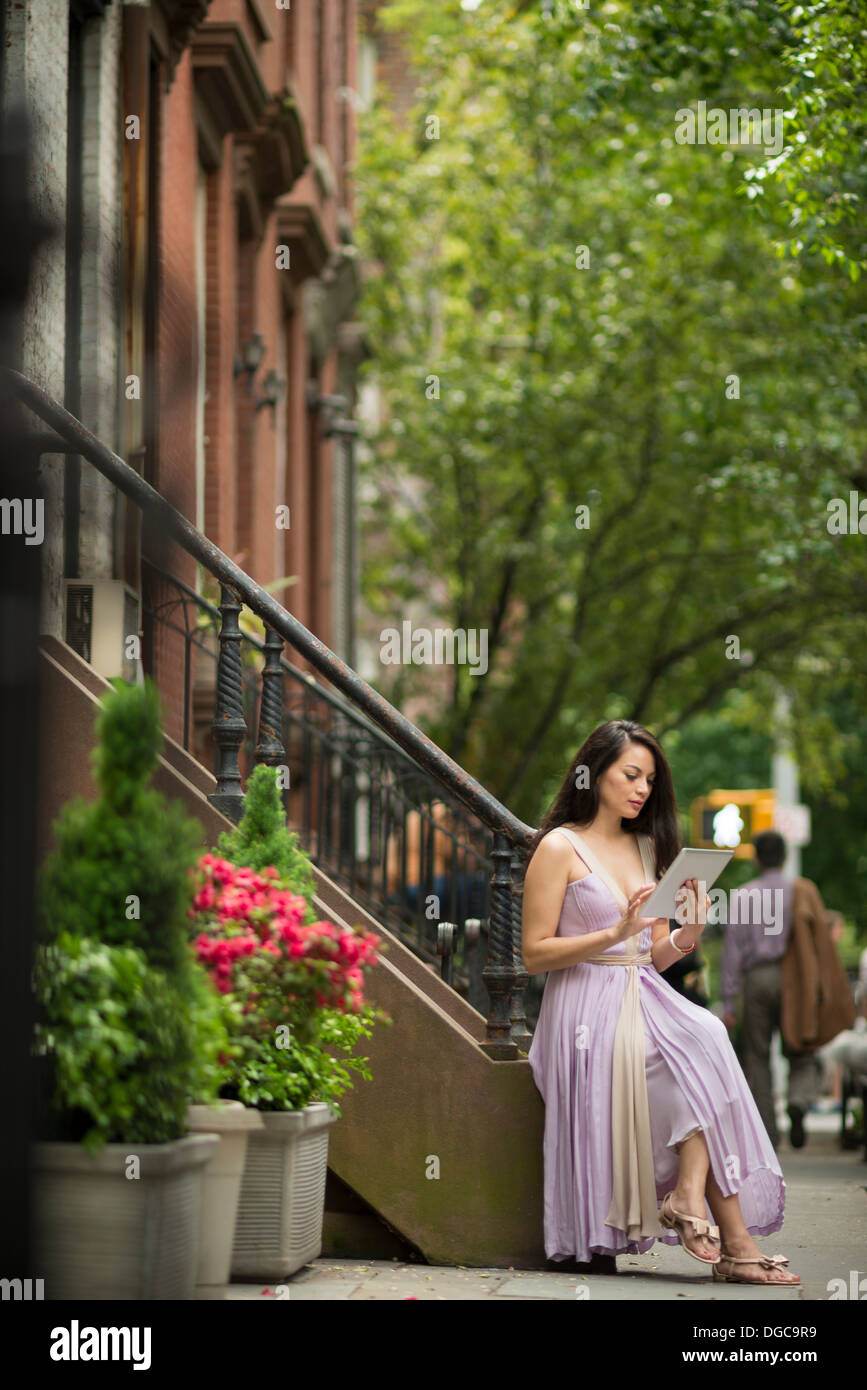 Mitte Erwachsene Frauen mit digital-Tablette von Brownstone Gebäude in Greenwich, New York Stockfoto