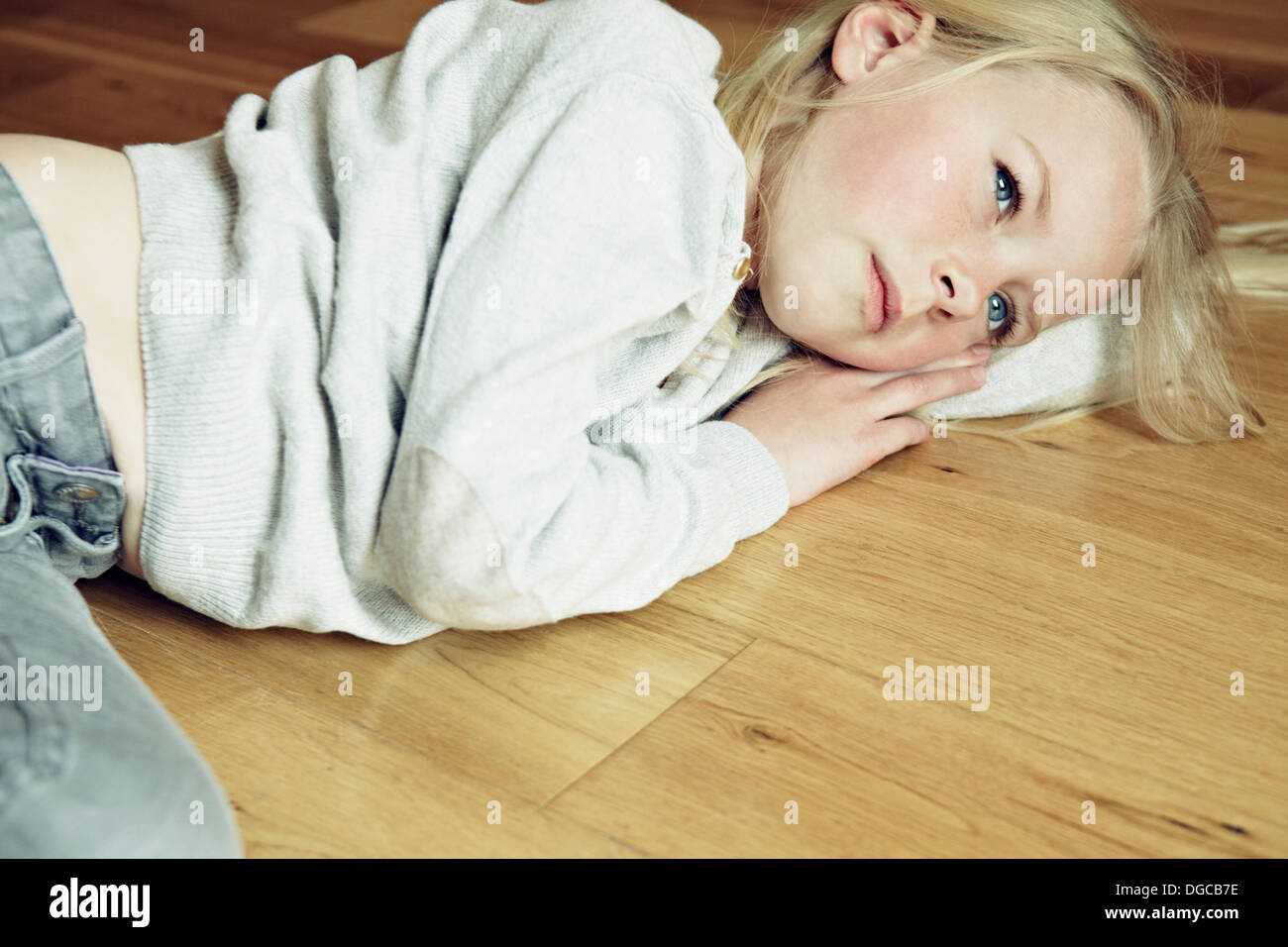 Junges Mädchen auf hölzernen Boden liegend, wegschauen Stockfoto