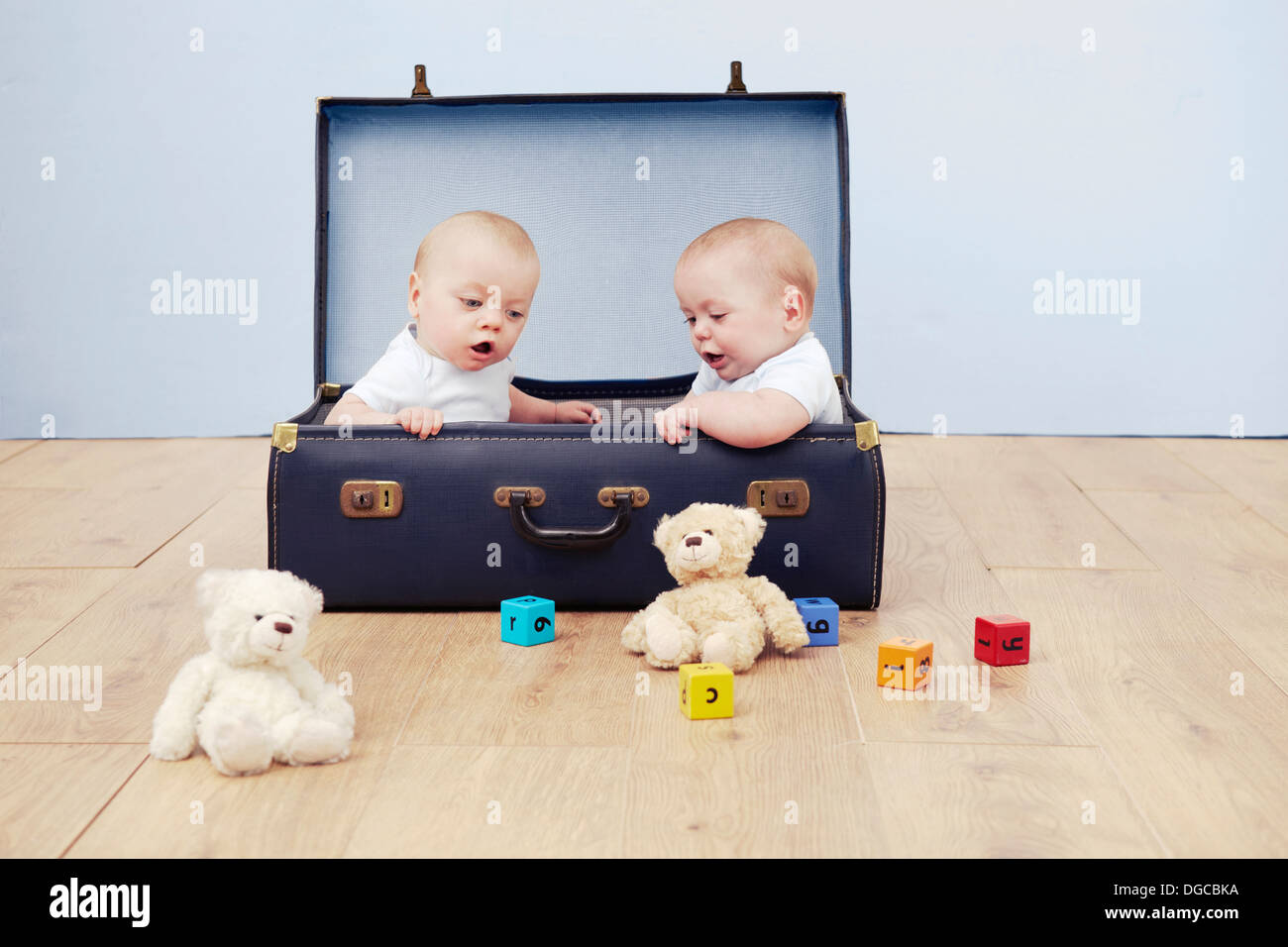 Zwei Baby-jungen sitzen im Koffer Blick auf Spielzeug Stockfoto