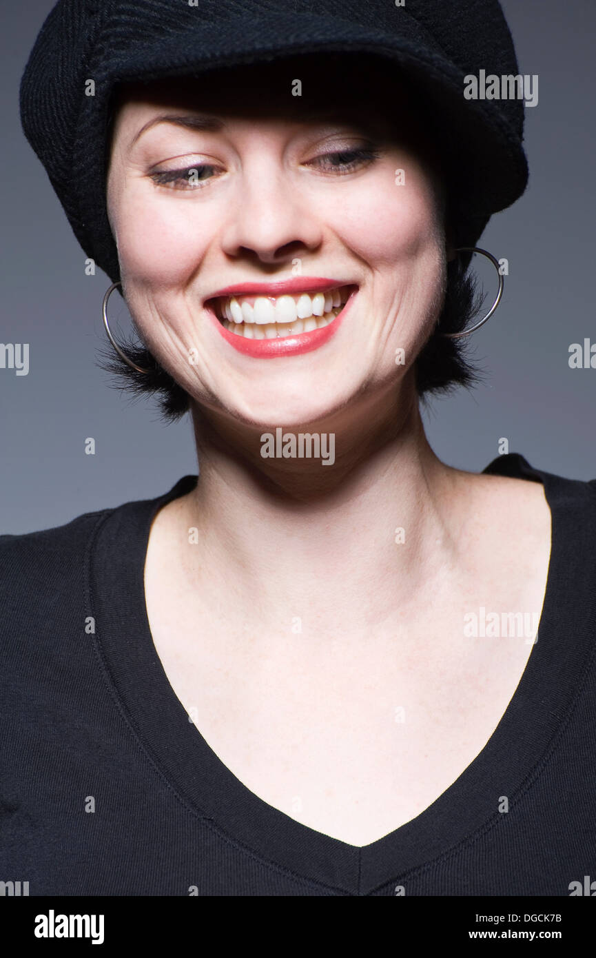 Junge Frau im schwarzen Hut schaut, lächelt Stockfoto