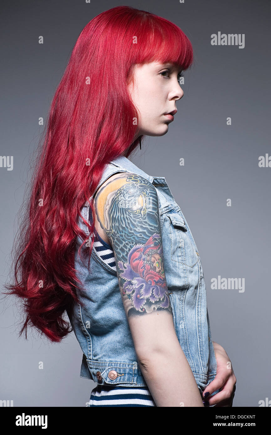 Junge Frau mit langen roten Haaren und Tattoos, Profil Stockfoto