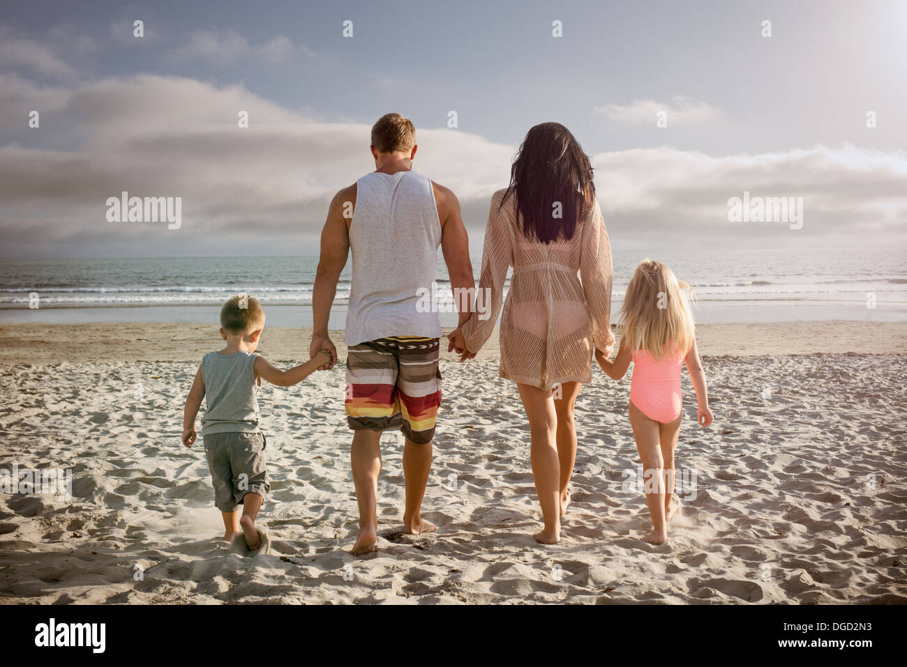 Junge Familie Hand in Hand zusammen am Strand, Rückansicht Stockfoto