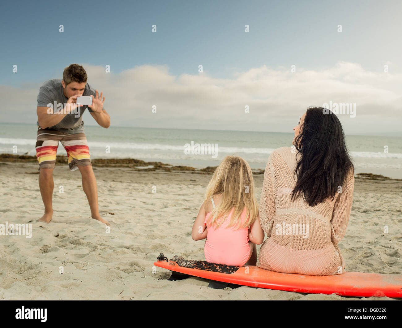 Mann, die Familie als das sitzen auf einem Surfbrett zu fotografieren Stockfoto