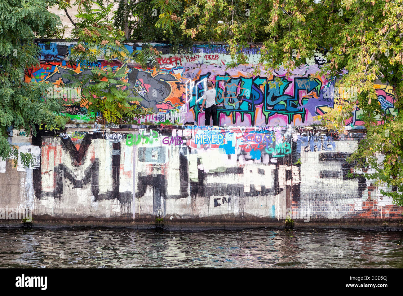 Graffiti-Künstler hinzufügen eines Tags auf die Graffiti bedeckt Wand an den Ufern der Spree, Berlin Stockfoto