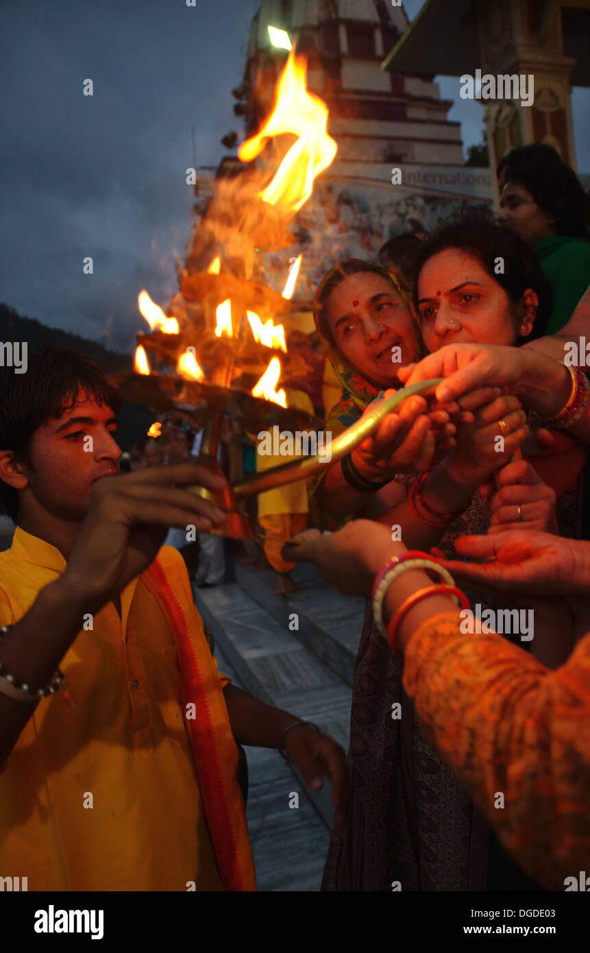 Anhänger, die die Wärme des heiligen Feuers von Aarti, Abend Ganga Aarti am Parmarth Niketan Ashram in Rishikesh, Indien Stockfoto