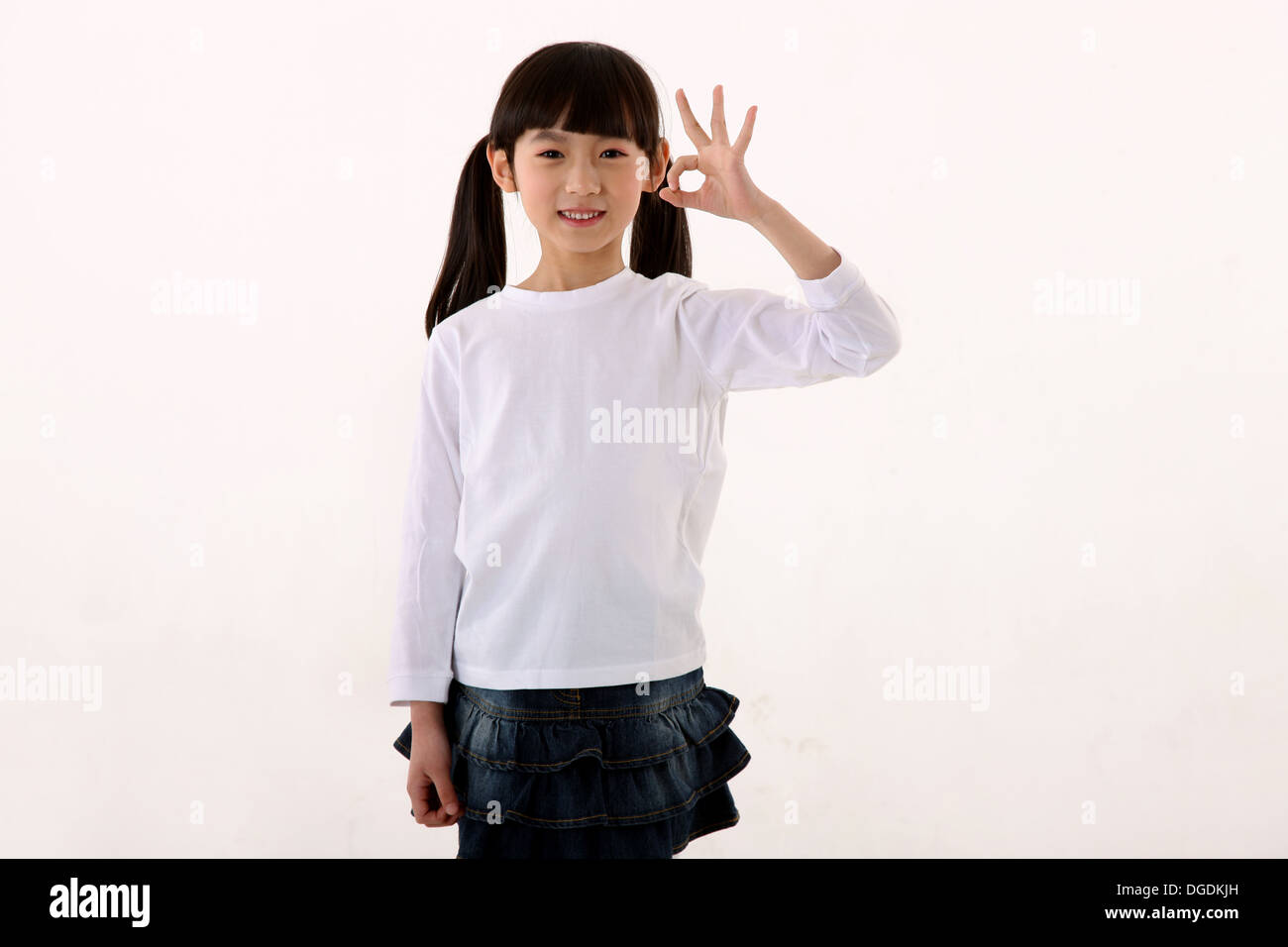 Asiatische Mädchen stehen, schaut in die Kamera mit OK Geste Stockfoto