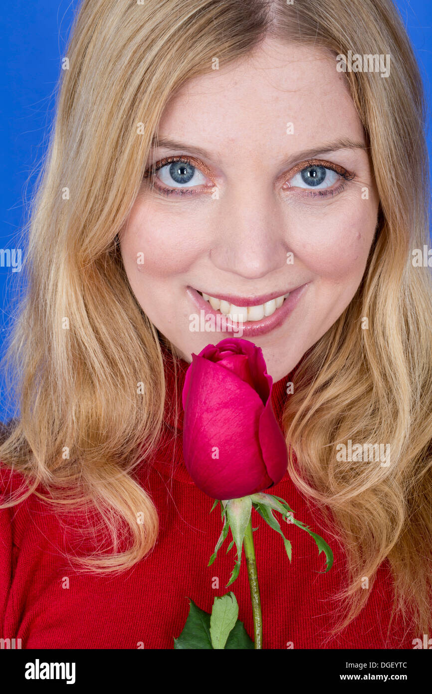 -Modell veröffentlicht. Attraktive junge Frau mit einer einzelnen roten Rose Stockfoto