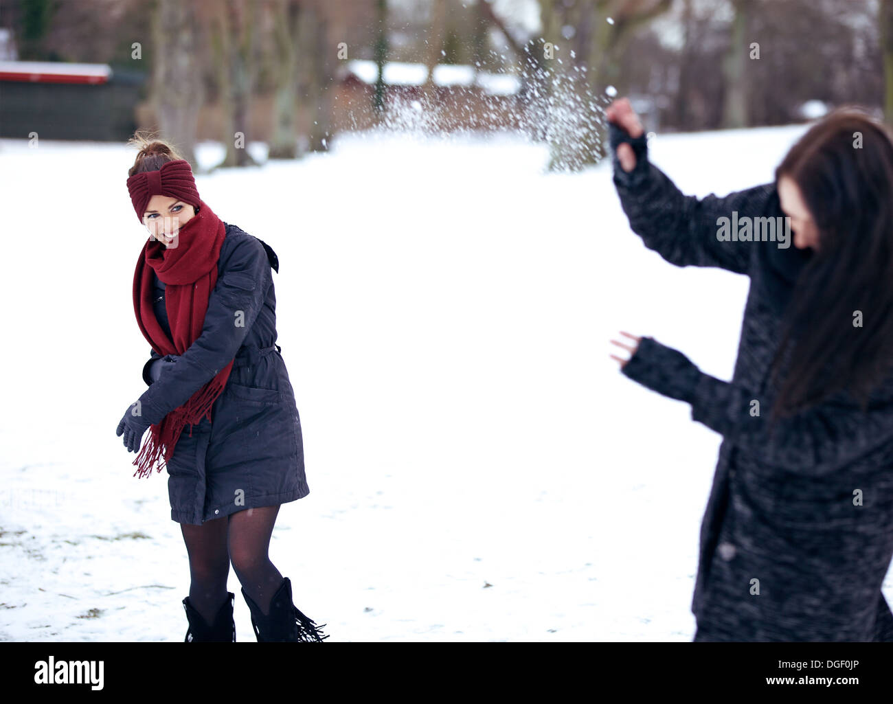 Fröhliche Frauen, die durch das Spielen im Schnee draußen genießen Stockfoto