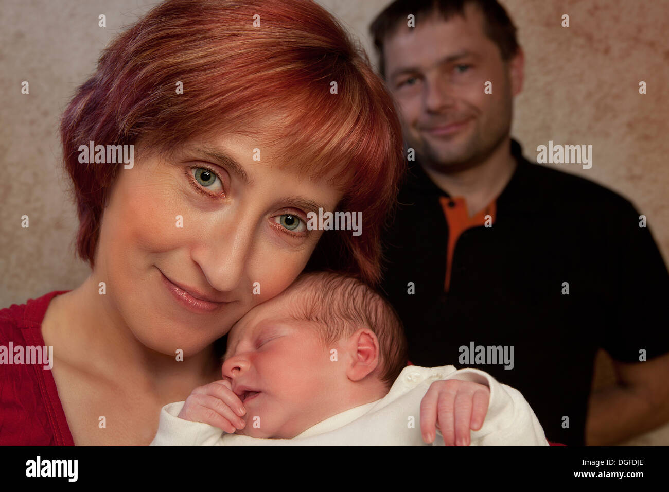 Familienporträt, Mutter mit ihrem Neugeborenen Baby jungen, Vater hinten, Deutschland Stockfoto