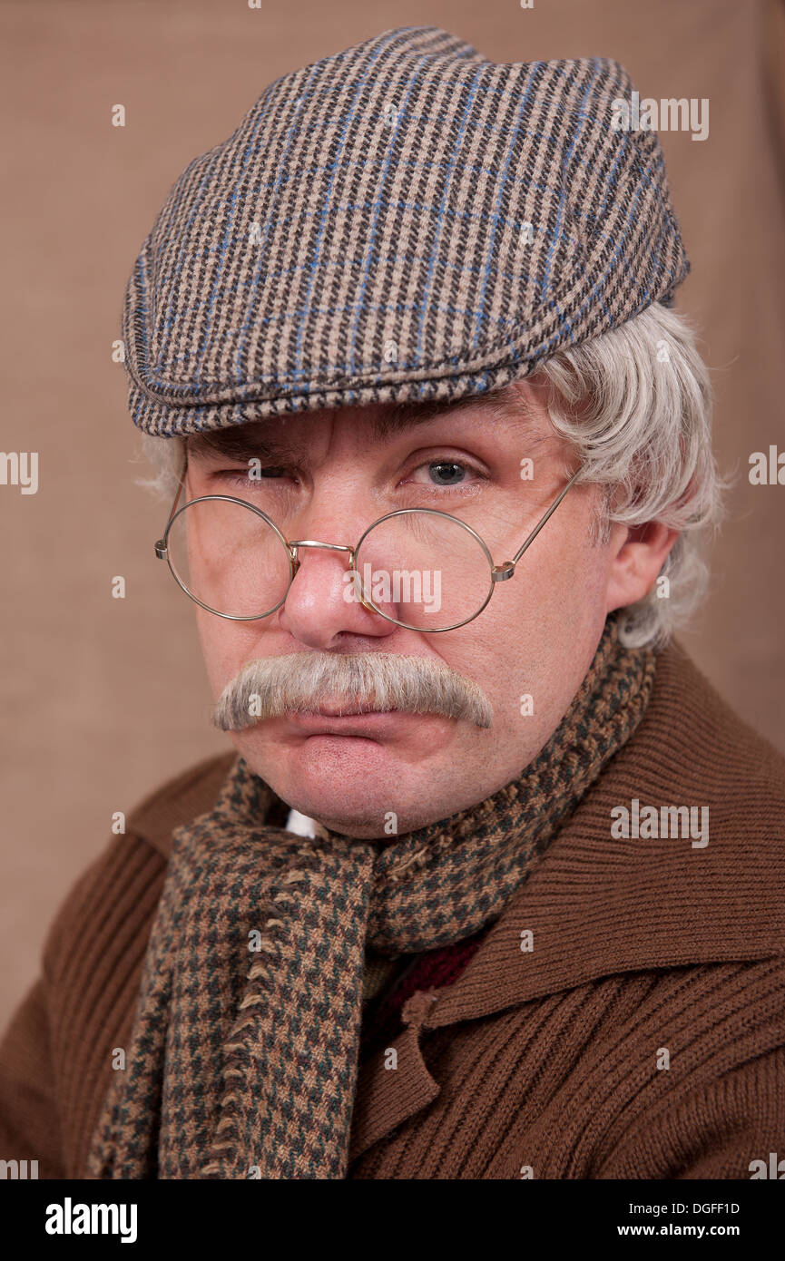 Porträt eines grauen Haaren alten Mannes tragen flache Kappe und bequeme Schal, einem braunen Hintergrund. Stockfoto