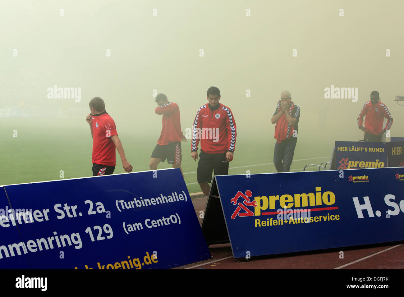 Sport, Fußball, Regionalliga West, 2013/2014, Rot Weiss Oberhausen gegen Rot Weiss Essen 2:0, Stadion Niederrhein in Oberhausen, Fußball-Fans von RW Essen feuern Rauchbomben, Rauch, Dunst, Nebel, Spieler und Wächter mit Gum Schilde, Gefahr für die Gesundheit Stockfoto