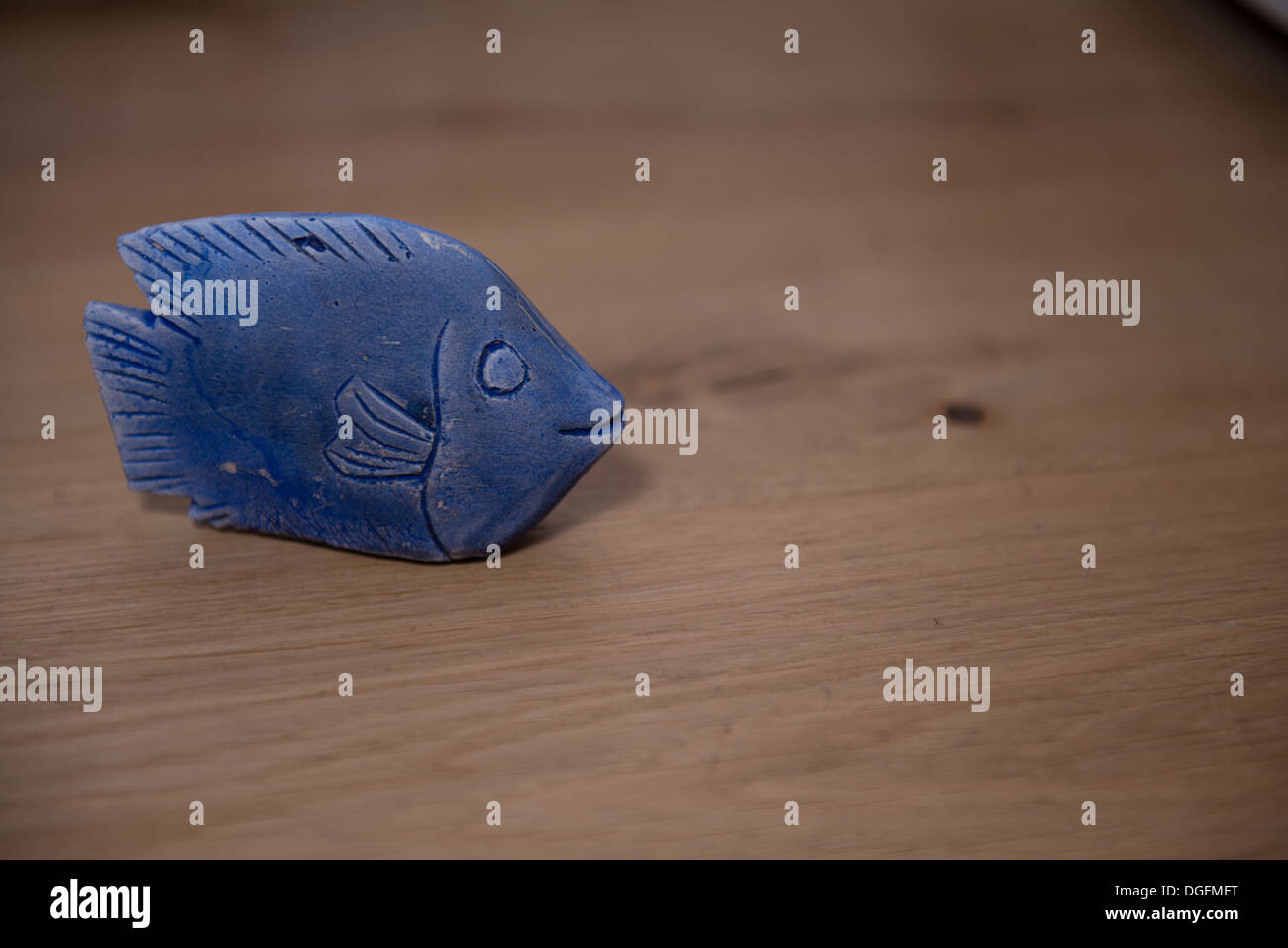 Blaue Miniatur-Statue eines Fisches auf einem hölzernen Hintergrund Stockfoto