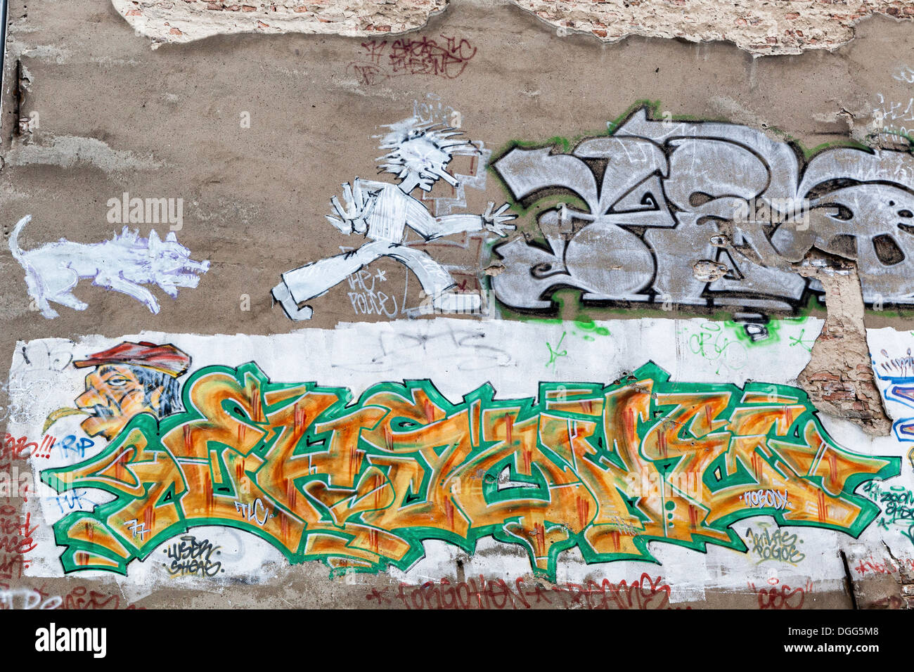 Street Art und Graffiti in Berlin auf einer alten Mauer mit rissigen Putz - Hund jagt Mann und tags Stockfoto