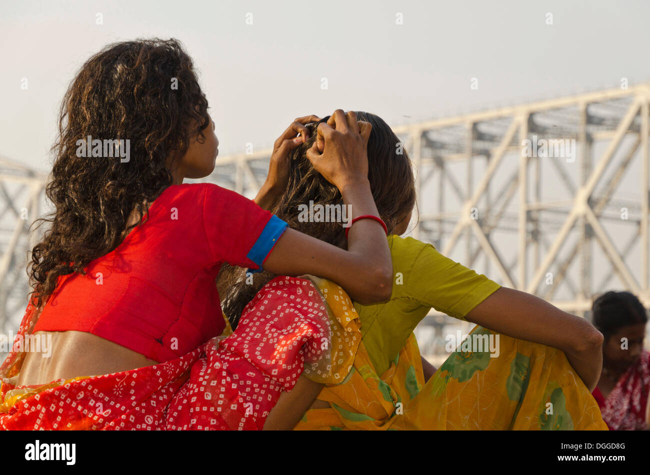Youg Frau sucht Läuse in den Haaren von einer anderen Frau, vor der Howrah Bridge, Kalkutta, Indien, Asien Stockfoto