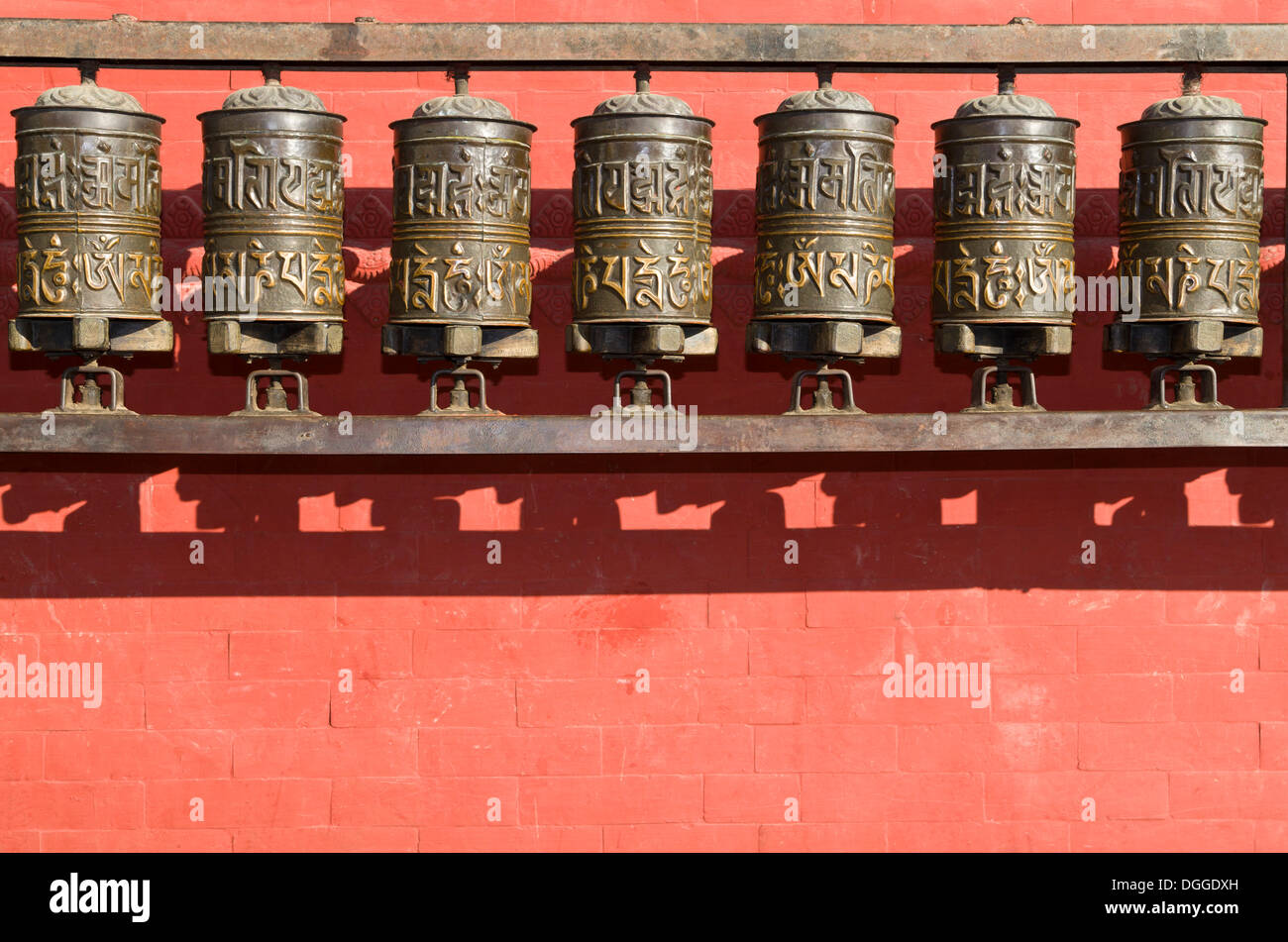 Buddhistische Gebetsmühlen vor einer roten Wand im Swayambhunath Stupa, Affentempel, Kathmandu-Tal, Kathmandu Stockfoto
