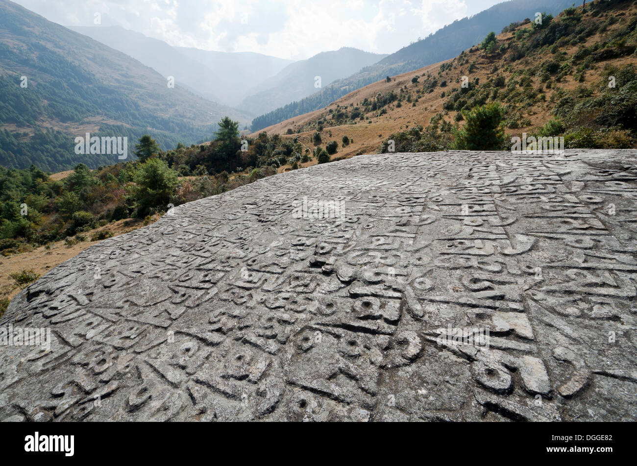 Mantra "Om Mani Padme Hum" geschnitzt in einem großen Felsen, Berge im Hintergrund, Junbesi, Solukhumbu Bezirk, Sagarmāthā Zone Stockfoto