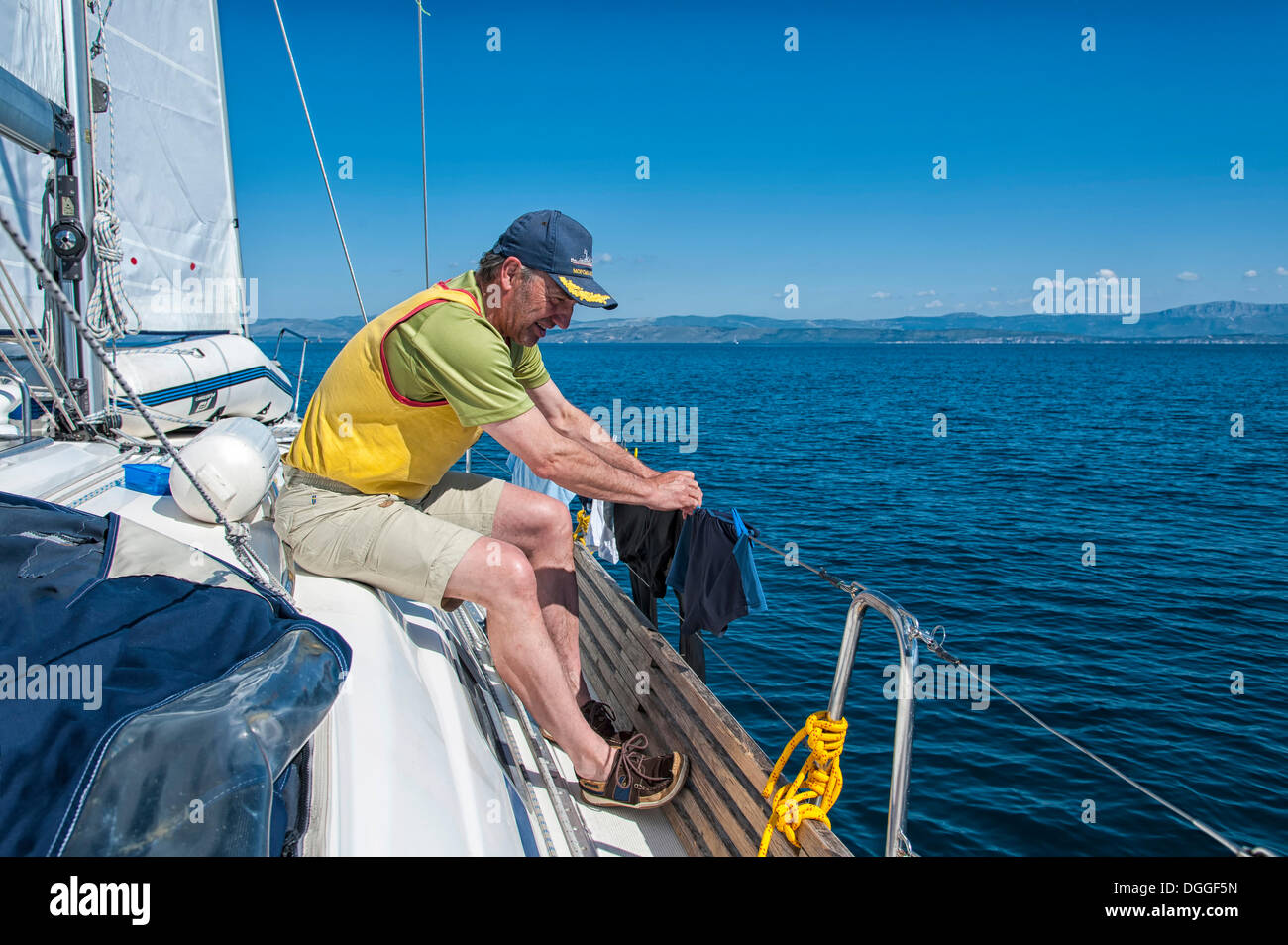 Mann, das Aufstellen von frischer Wäsche auf der Schiene von einer Segelyacht, Adria, Kroatien, Europa Stockfoto
