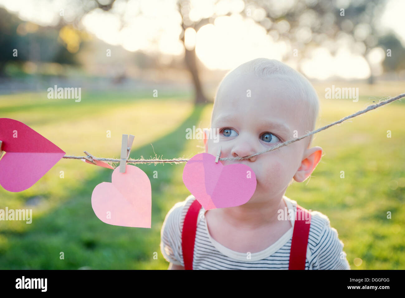 Kleiner Junge mit Blick auf Herzformen auf Wäscheleine Stockfoto