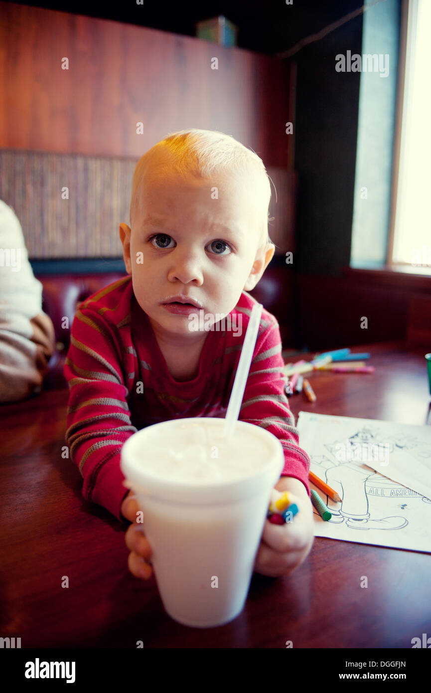 Kleiner Junge für Milchshake im Café zu erreichen Stockfoto