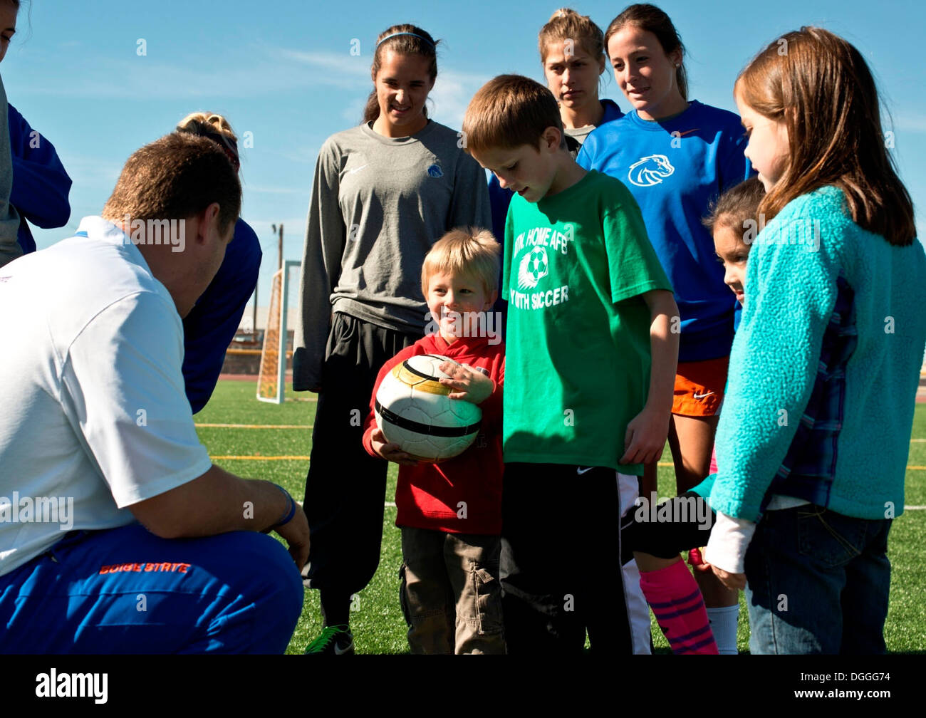 Ed Moore, Boise State University Damen Fußball Team Co-Trainer, veranschaulicht Basis Kinder, mit der Innenseite der ihre Stollen während einer Fußball-Klinik für Soldaten und deren Angehörige in Mountain Home Air Force Base, Idaho, 5. Oktober 2013 übergeben. Die Broncos besucht bas Stockfoto