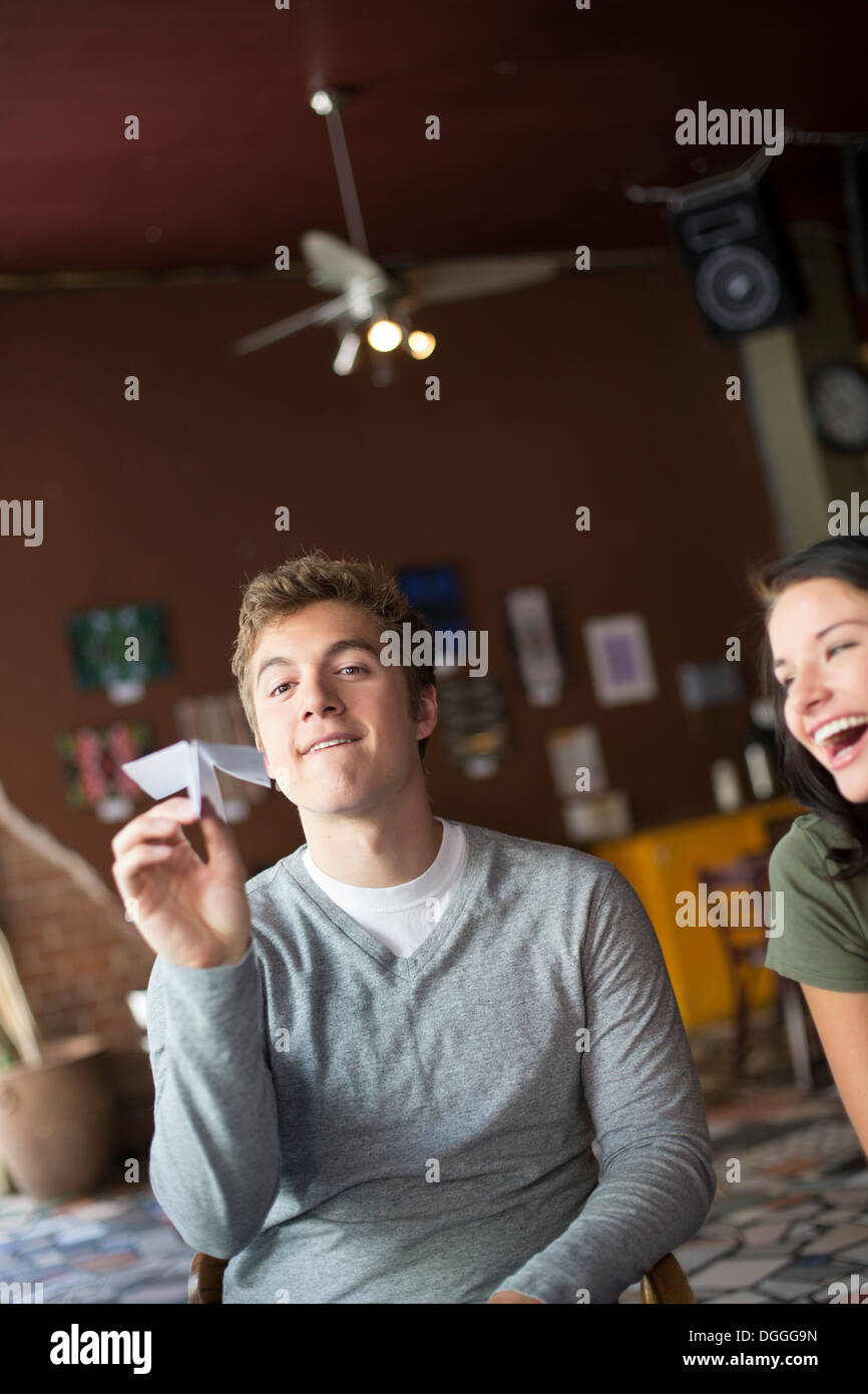 Junger Mann hält Papierflieger im Kaffeehaus Stockfoto