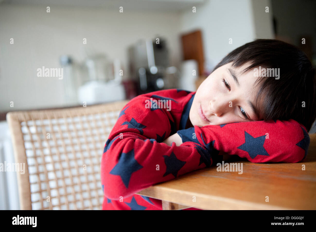 Junge im Pyjama auf Ellbogen auf den Tisch Stockfoto