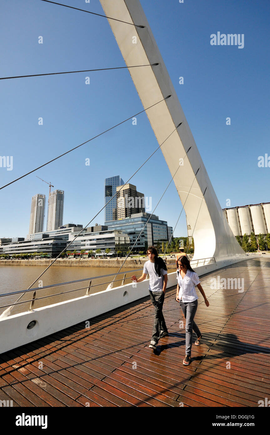 Touristen, die zu Fuß auf einer modernen Hängebrücke Brücke Puente De La Mujer, Frauen Brücke, im alten Hafen von Puerto Madero Stockfoto