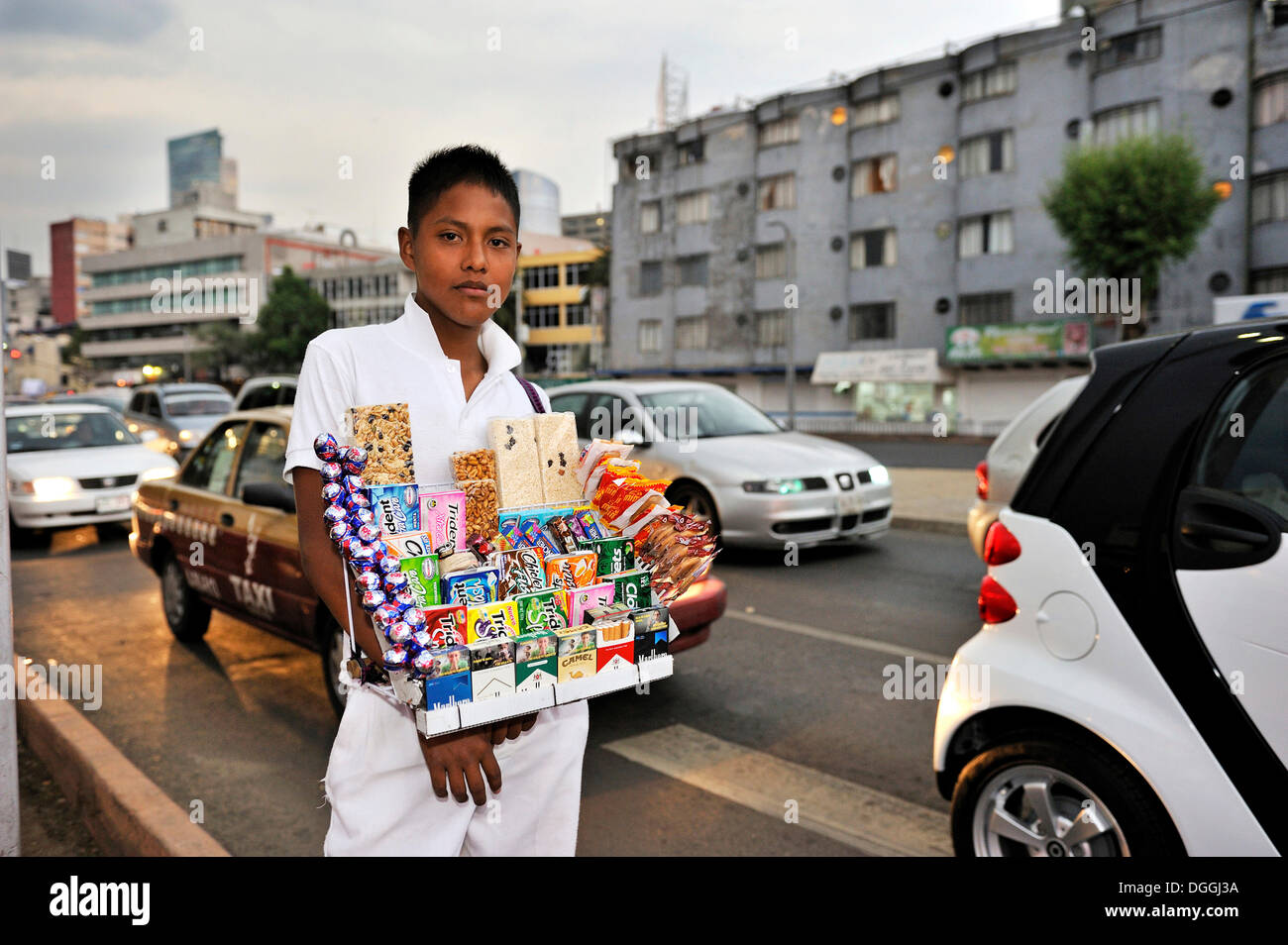 Junge Verkauf von Süßigkeiten und Zigaretten an einer Straßenkreuzung, um das Einkommen seiner Familie, Mexiko-Stadt Stockfoto