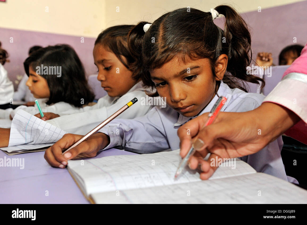 Lehrer, die Korrektur der Arbeit einer Schülerin an einer Schule der christlichen Gemeinde in Lahore, Punjab, Pakistan, Asien Stockfoto
